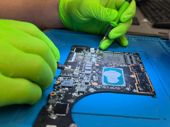 Technicien réparation carte mère MacBook gants verts
