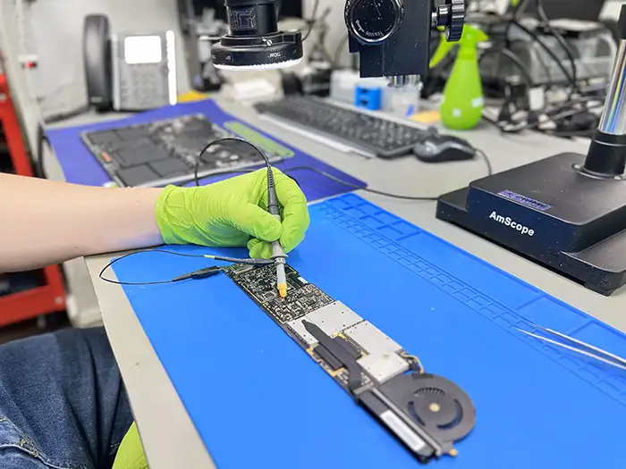 Technicien microsoudure carte mère MacBook sous microscope AmScope